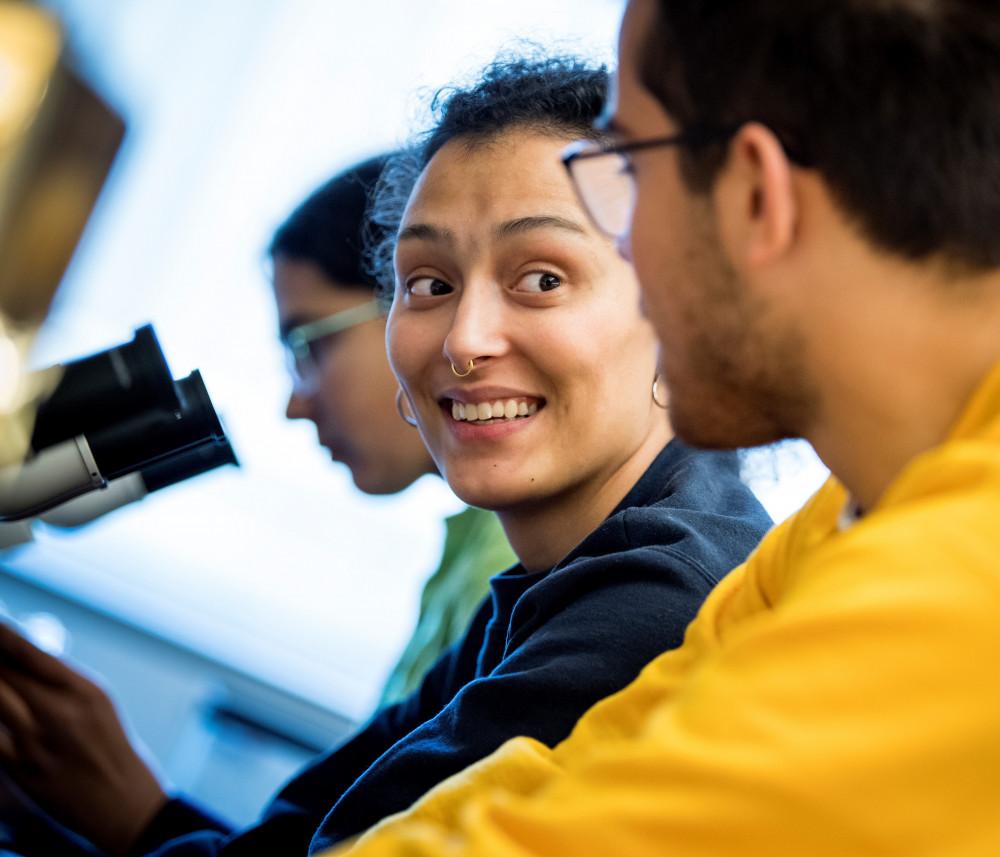 Two 学生s working together at microscopes.